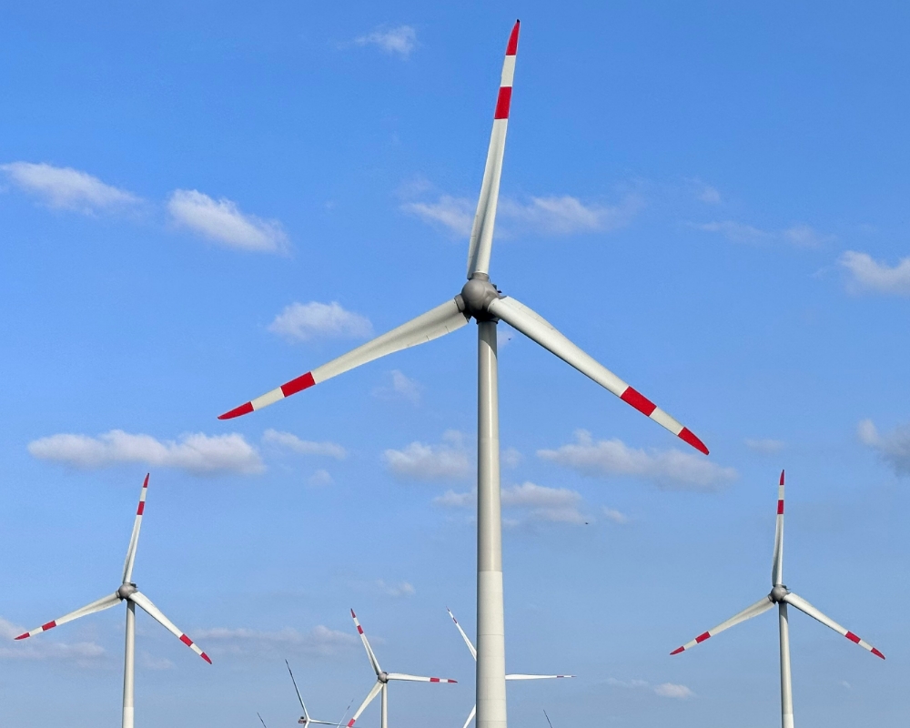 Onshore wind farm with wind turbines generating renewable energy, set against a blue sky
